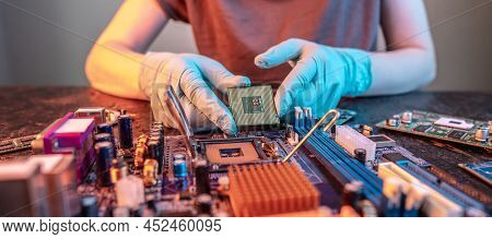 The Engineer's Gloved Hand Is Holding The Cpu Chip Against The Background Of The Motherboard. Concep