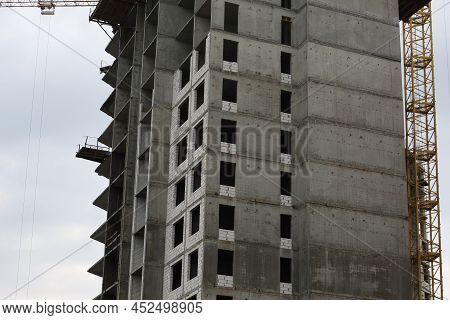 Construction Yellow Crane Builds A Tall Multi-apartment Residential Building From White Bricks And C