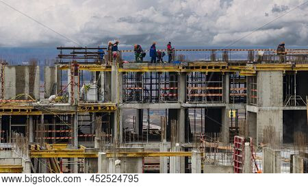 Monolithic Frame Construction Of The Building. Workers Working At The Construction Site At Home. The
