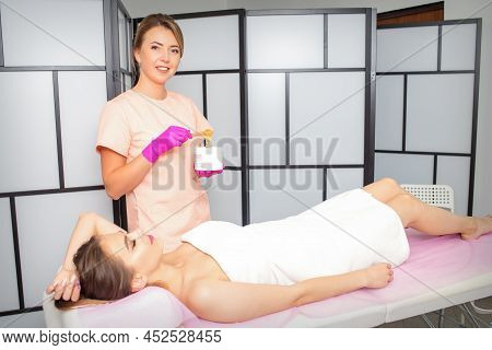 Sugaring. The Beautician Takes The Sugar Paste From The Jar With A Spatula. Lying Woman Customer Wai