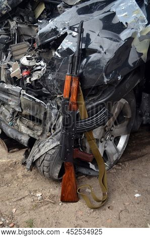 AKM(Avtomat Kalashnikova) version of Kalashnikov assault rifle and car wreck. April 7, 2022. Kiev Region, Ukraine