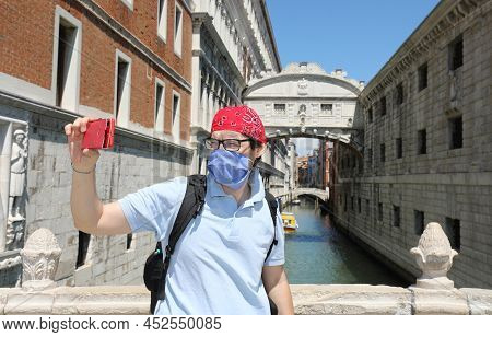 Young Man Take A Selfie With Mask During Lockdown In Venice In Italy And The Brdige Of Sighs In Back