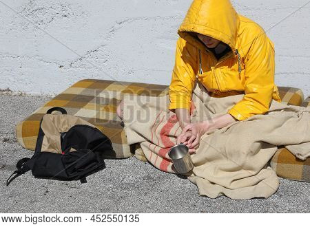Beggar Sitting On A Filthy Mattress In The Street Asking For Charity And Alms