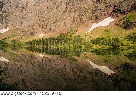 Morning Star Lake Mirrors The Nearby Hill Side On Quiet Morning In Glacier National Park