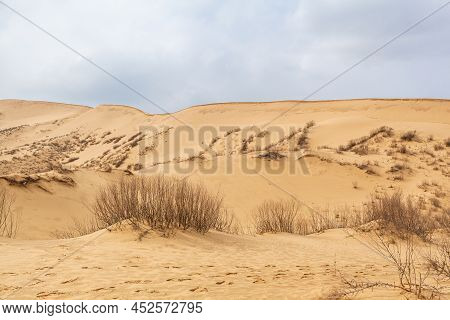 Sarykum Dune. Dagestan, Russia. A Unique Sandy Mountain In The Caucasus On A Cloudy Day. Grass Grows
