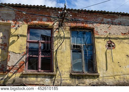 A Shabby, Rough, Cracked Wall, With Windows. The Concept Of Devastation Caused By War, Poverty