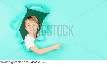 Kid Looks Through Hole. Blonde Boy Looks Through Ripped Paper. Boy In Red Paper Hole Pointing With F