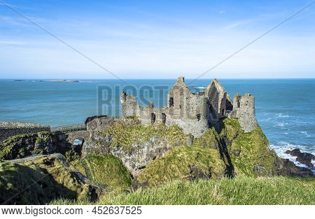 Bushmills, Northern Ireland, March 2022. Dunluce Castle With Blue Sea Background In A Sunny Day.