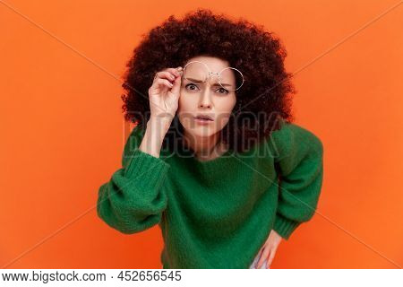 Curious Woman With Afro Hairstyle Wearing Green Casual Style Sweater Raising Her Optical Glasses, Wa