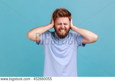 Dont Want To Listen. Portrait Of Despaired Man Irritated By Loud Noise Covering Ears And Grimacing I