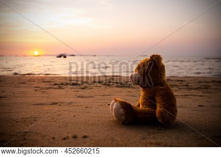 Single Teddy Bear On Sand Beach At Coast Of Water Sea Shore Nature Sunset Background. Vintage With F