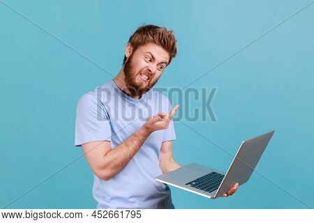 Portrait Of Bearded Man Showing Middle Finger To Laptop Screen, Aggressively Communicating On Video 