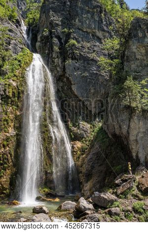 Beautiful Theth waterfall near Theth village in Albanian alps mountains. Majestic cascade waterfall into the forest in slow motion, Accursed mountains, Albania