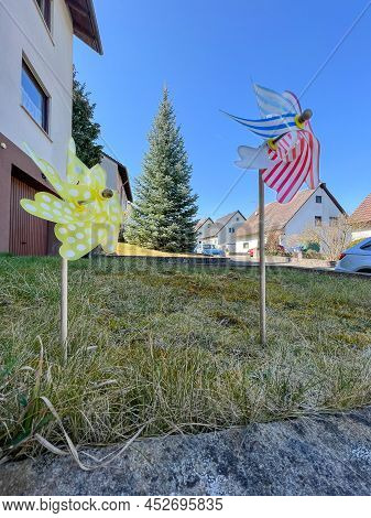 Two Colorful Pinwheel With Houses In The Background