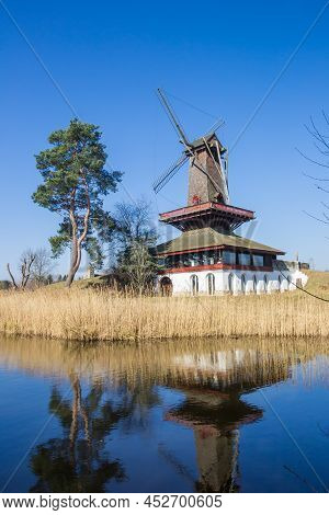 Historic Windmill Reflecting In The Water In Gifhorn, Germany