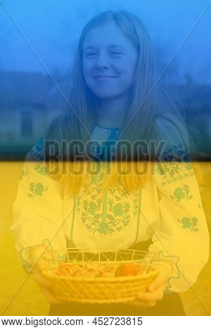 Defocus Ukrainian Girl In Vyshyvanka Holding Basket Of Colored Red Eggs On Ukrainian Flag Background
