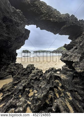 View Of The Beach Of Barro Through A Hole In A Rock Eroded By The Sea At Low Tide, Barro, Llanes, As