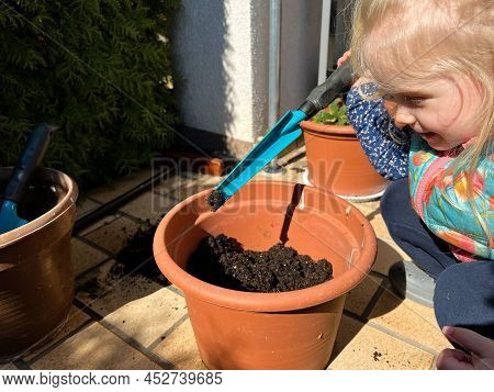A Toddler Playing With The Ground Or Planting