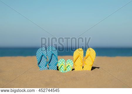 Multicolor Flip-flops On The Sandy Baech Against Sea And Sky