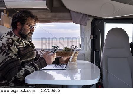 Adult Man Working With Laptop Inside A Camper Van. Freedom Remote Worker Lifestyle. Smart Working Wi