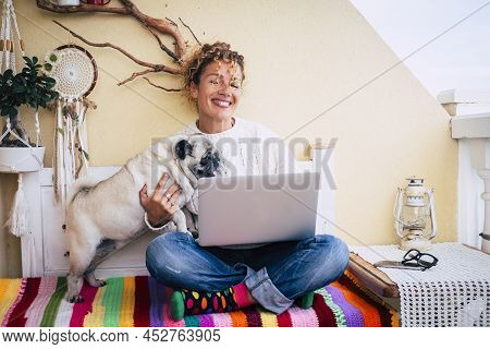 Cheerful Woman Playing With Her Pet Dog Pug While Working On Laptop From House Terrace. Woman Having