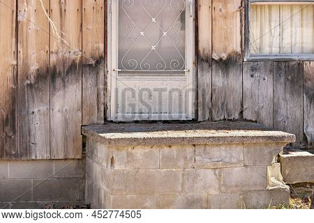 Close Up Of Weathered Wood Siding Beginning To Rot Around Front Step Of Cottage Or House