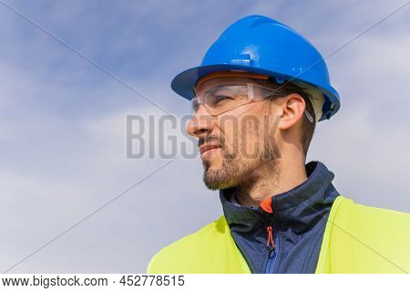 Portrait Of A Worker Or Engineer, With A Firm Gaze To The Sky, Looking To The Future Proud Of His Wo