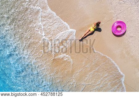 Aerial View Of Young Woman With Pink Swim Ring On The Sandy Beac