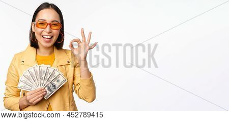Microcredit And Loans Concept. Happy Stylish Korean Girl Showing Okay Sign, Ok And Money, Dollars Ca