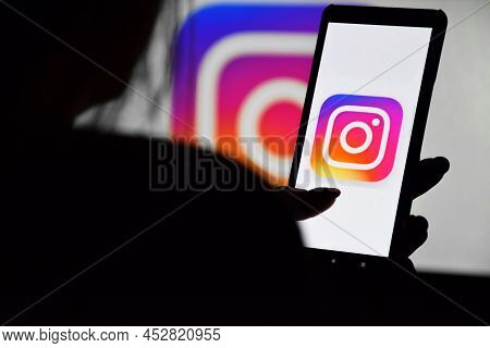 A Phone With A Instagram Screen In The Hands Of A Young Girl Against The Background Of A Monitor. Se