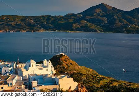 View of Plaka village on Milos island with traditional greek white houses with Greek Orthodox christian churck on sunset. Plaka town, Milos island, Greece