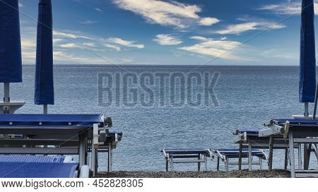 Deckchairs With Umbrellas On The Italian Beaches Of The Western Ligurian Riviera, In Spotorno, In Th