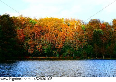 Autumn Colored Forest Around Blue Holzmaar With Light Waves