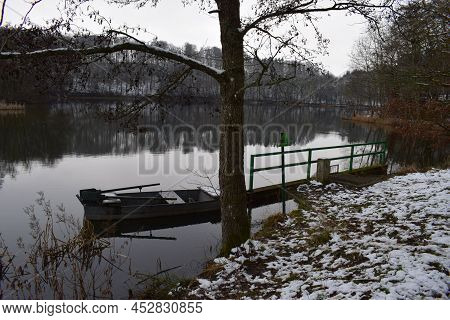 Boat On A Gloomy Lake In Winter With Light Snow