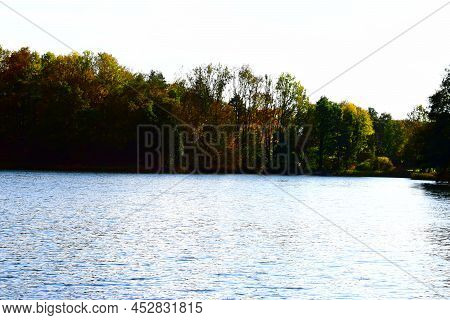 Sun Lighting Up The Caldera Lake Holzmaar Between Autumn Forest