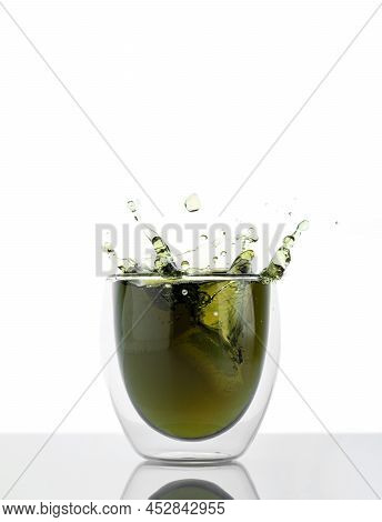 Glass Of Water With Chlorophyll Extract Against White Grey Background. Liquid Chlorophyll In A Glass