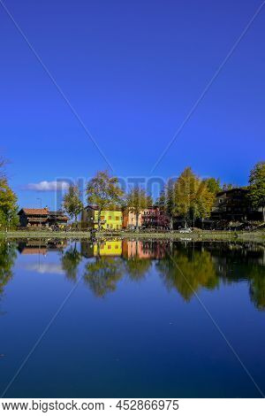 Colorful Houses On The Lake On A Sunny Bright Day. Water Reflections. Landscape Background. Cerreto 