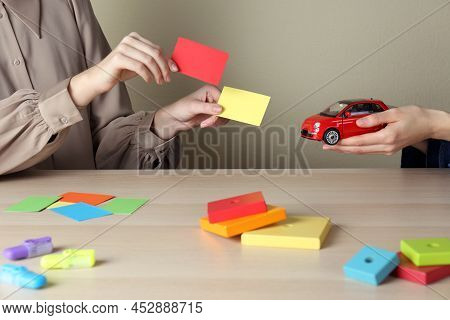 Women With Toy Car And Color Papers At Wooden Table Indoors, Closeup. Aba Therapy Concept