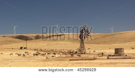 Oude gebroken wind pomp en nieuwe windgenerators vervormd door de hete lucht. Zuid-Australië.
