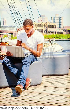 Young African American Man Traveling In New York, Wearing White T Shirt, Blue Pants, Boot Shoes, Sit