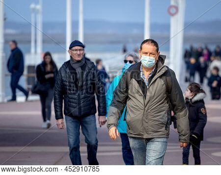 Arcachon, France - February 22, 2022: Middle Aged Men Walking In The Streets Of Arcachon Wearing Fac