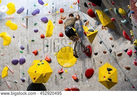 The Climber Trains On The Artificial Rock Wall With Insurance In Bouldering Gym, April 2022, Prague,
