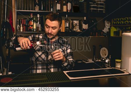 Bartender Preparing Cocktail Behind Bar Counter, Pouring Berry Liquor Into Glass