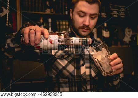 Bartender Pouring Grenadine Syrup From Bottle Into Glass With Ice, Preparing Tequila Sunrise Cocktai