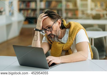Frustrated Male Manager Is Sitting At The Work Desk, Sed About Failed Project. Middle Aged Businessm