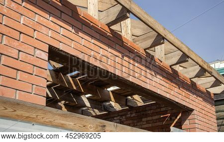 A Private Residential Building Under Construction With A Wooden Frame Roof Structure. Unfinished Bri