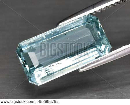 Natural Gemstone Blue Aquamarine In Tongs On A Gray Background