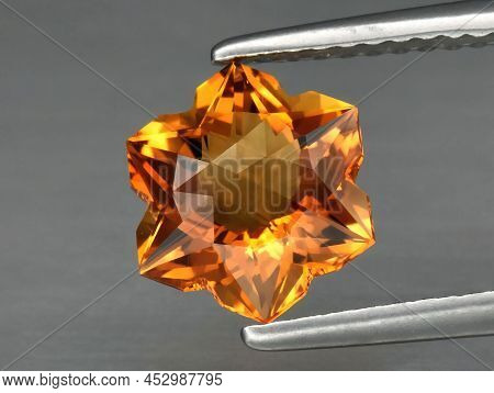 Natural Gemstone Yellow Citrine In Tongs On A Gray Background