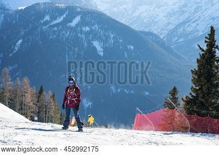 Snowboarder Standing On Snowy Mountain Slope At Winter Resort On Sunny Day