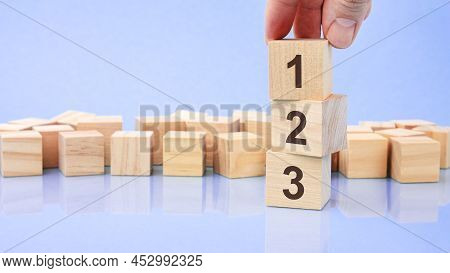Hand Holding Wood Cube Block With 123 Digits. The Inscription On The Cubes Is Reflected From The Sur